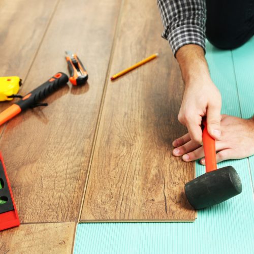 Carpenter worker installing laminate flooring in the room Carpenter worker installing laminate flooring in the room